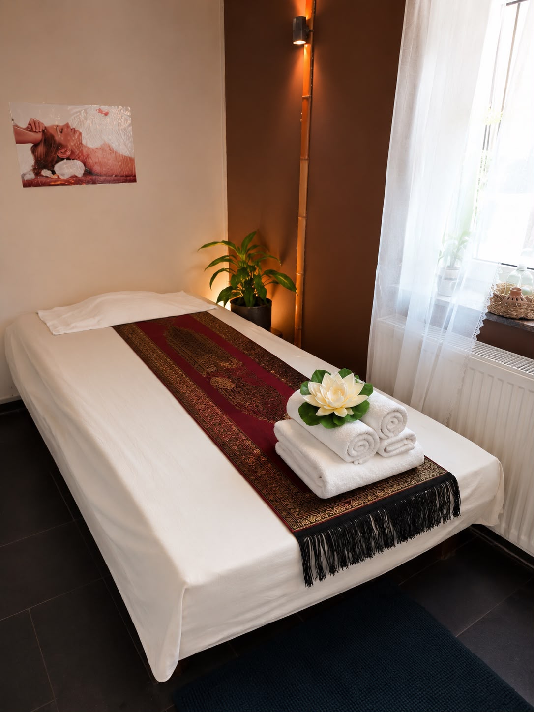 Behandlungsraum mit Massageliege, frischen Handtüchern und Lotusdeko